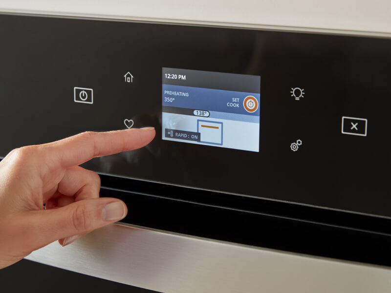 A person selecting a setting on an oven control panel A person selecting a setting on an oven control panel