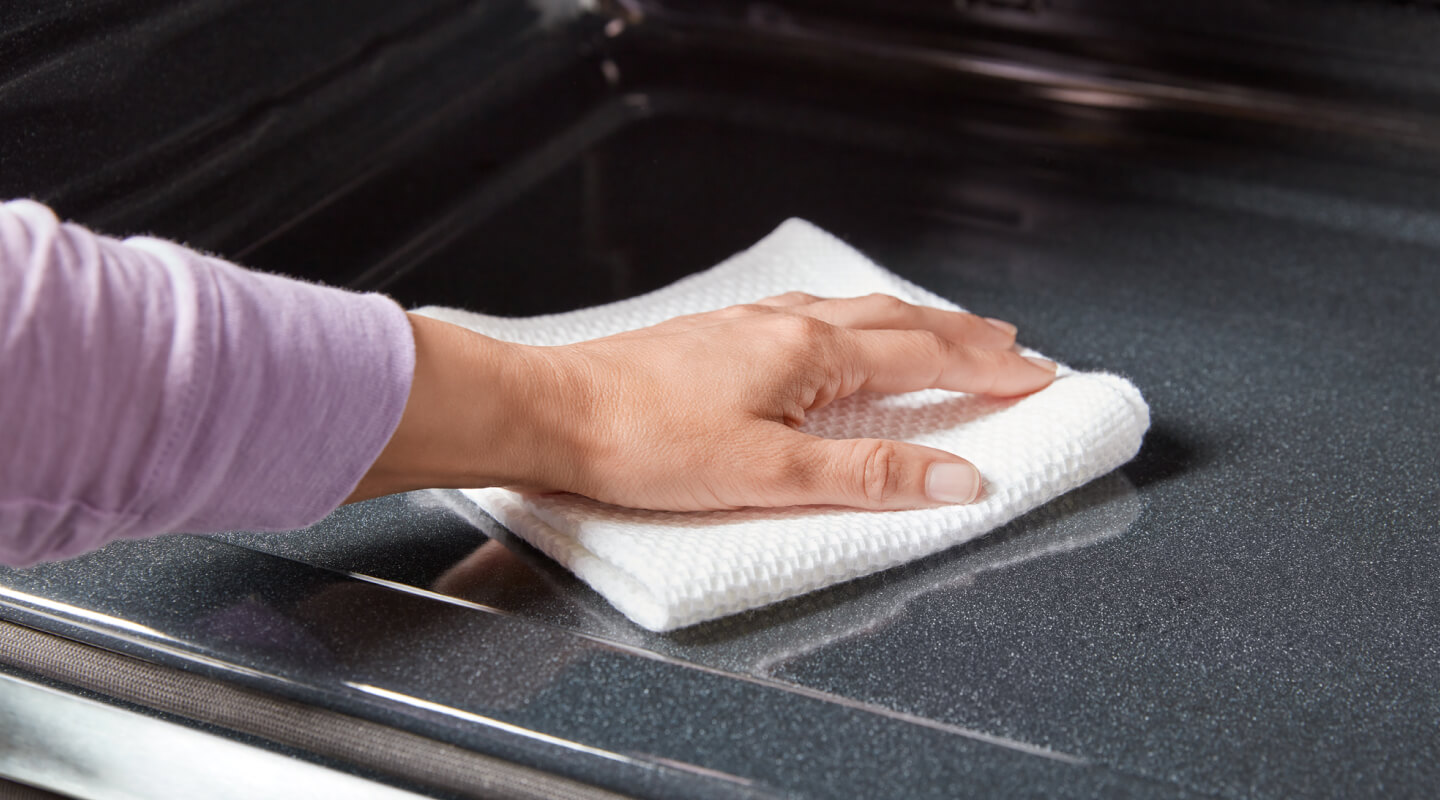 A person cleaning the inside of an oven A person cleaning the inside of an oven