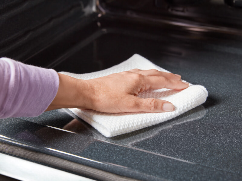 A person cleaning the inside of an oven A person cleaning the inside of an oven