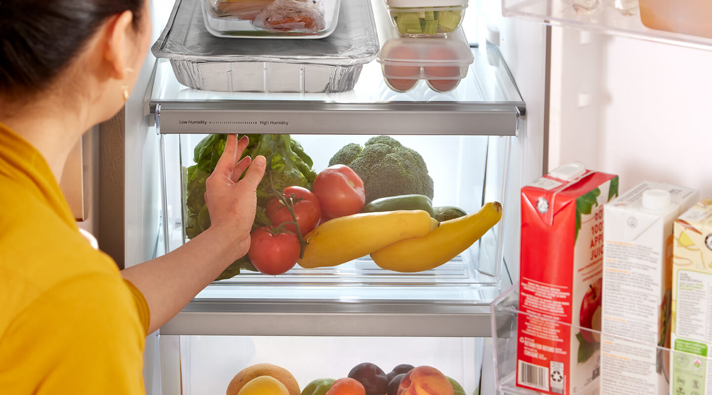 Someone adjusting the humidity setting on a refrigerator storage drawer Someone adjusting the humidity setting on a refrigerator storage drawer