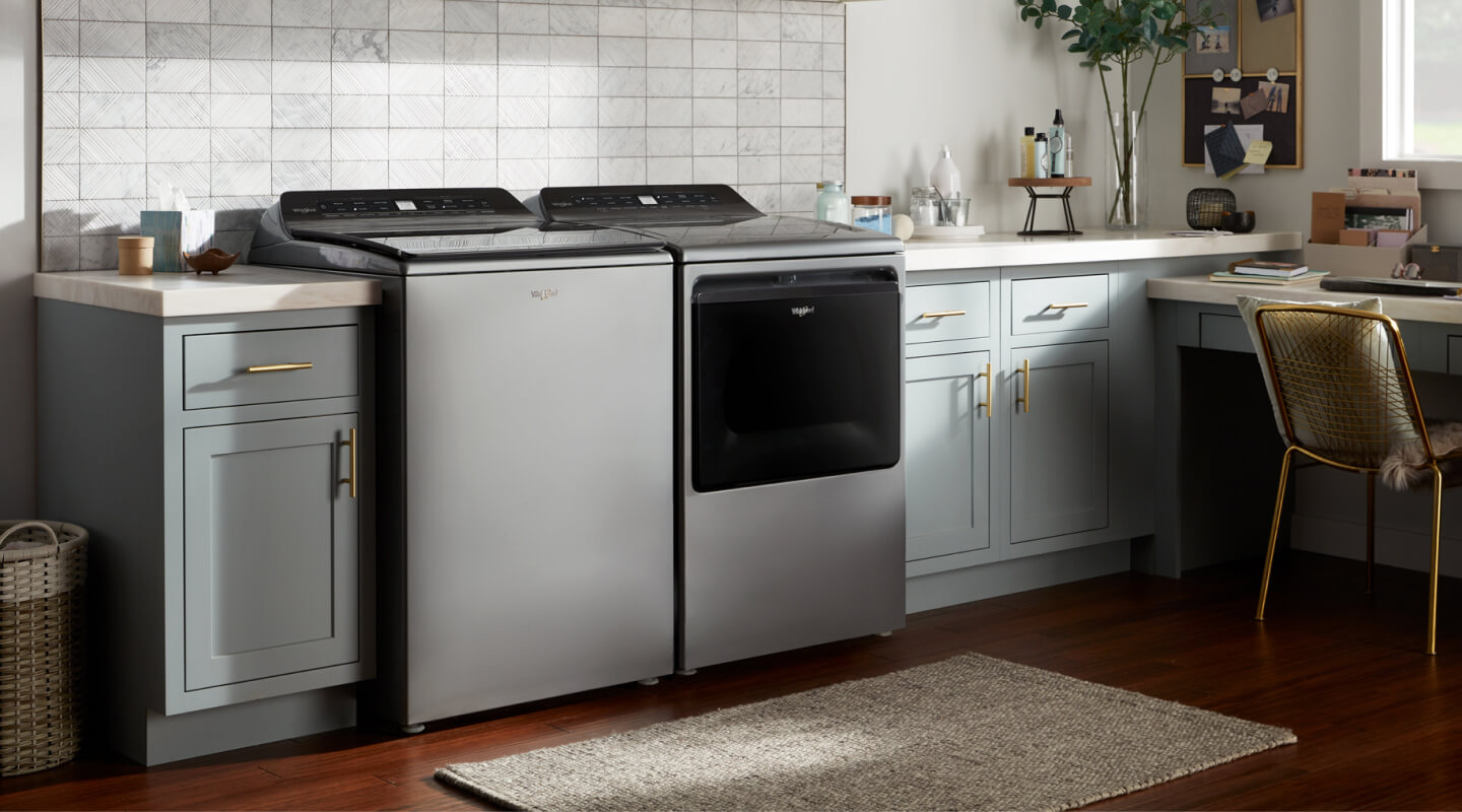 Whirlpool® Top Load Washer and Dryer pair in front of white backsplash