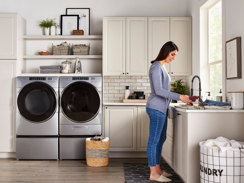 Woman in a laundry room with stainless steel Whirlpool® front load washer and dryer set Woman in a laundry room with stainless steel Whirlpool® front load washer and dryer set