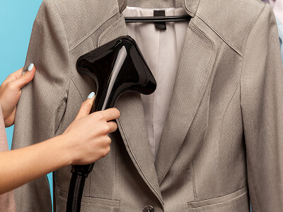 Person using a garment steamer on a suit jacket