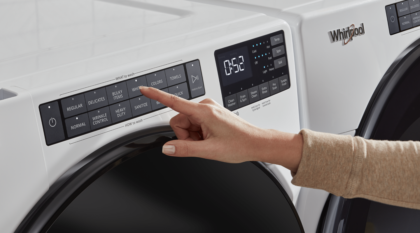Woman selecting a wash cycle on a white front-loading washer