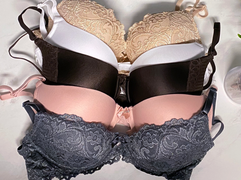 Variety of different colored bras next to clothespins and a plant