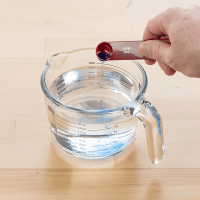 Person creating a cleaning solution in a measuring cup