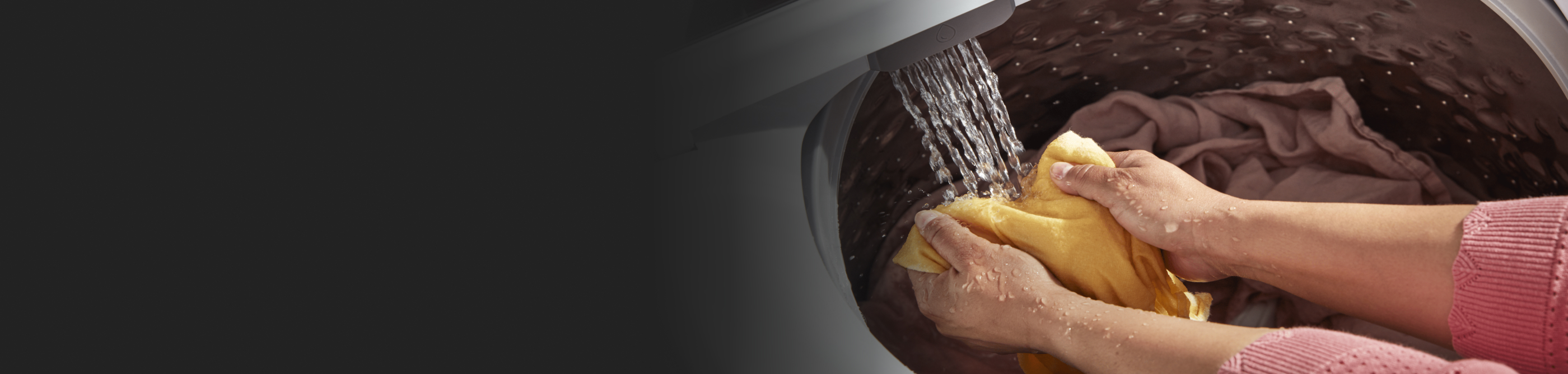 Person pretreating yellow clothing in washer water stream.