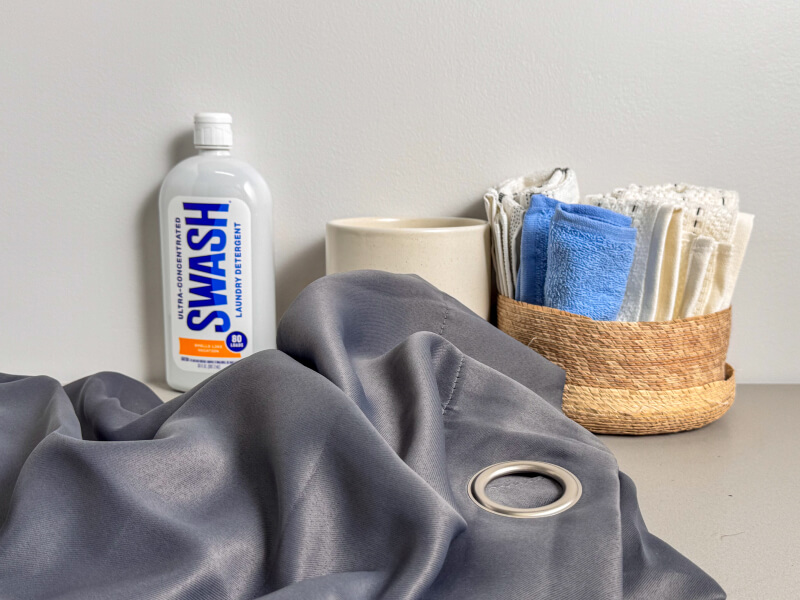 Grey curtains near a bottle of Swash® Laundry Detergent Grey curtains near a bottle of Swash® Laundry Detergent