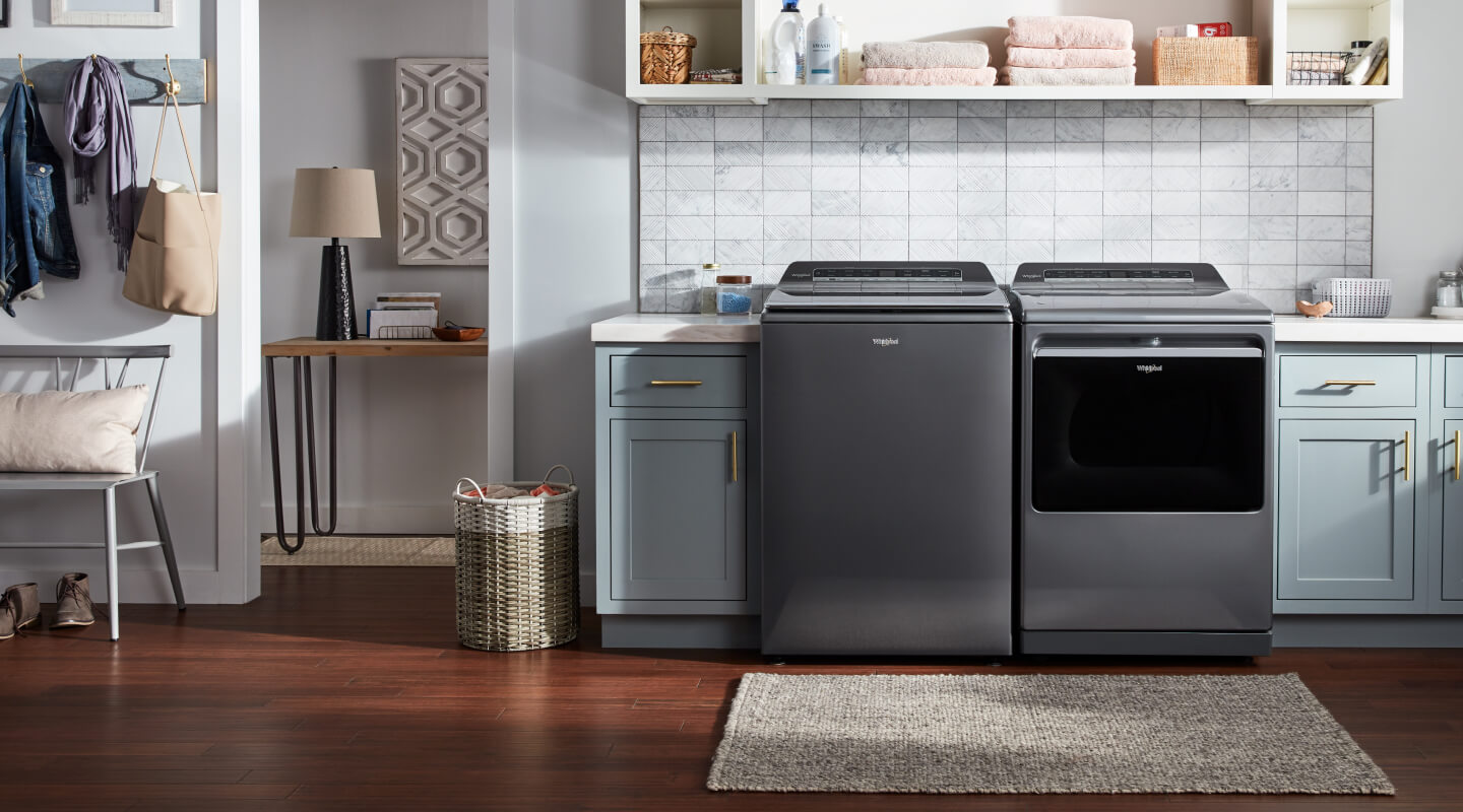 Laundry room with a grey top load washer and dryer set by Whirlpool brand Laundry room with a grey top load washer and dryer set by Whirlpool brand