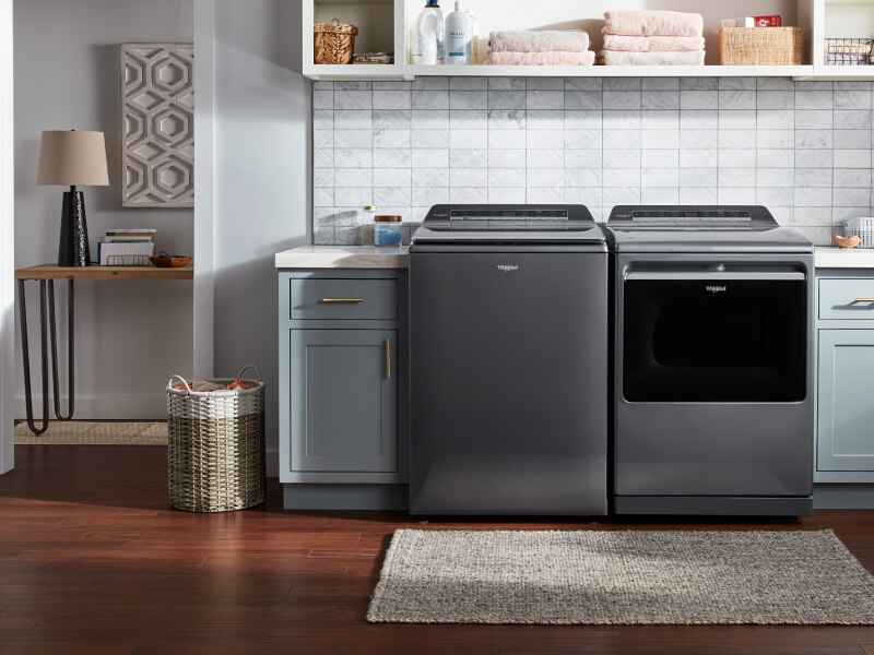 Laundry room with a grey top load washer and dryer set by Whirlpool brand Laundry room with a grey top load washer and dryer set by Whirlpool brand