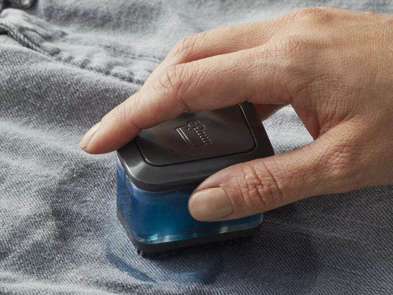 A closeup of a hand of a woman spot cleaning a garment. 