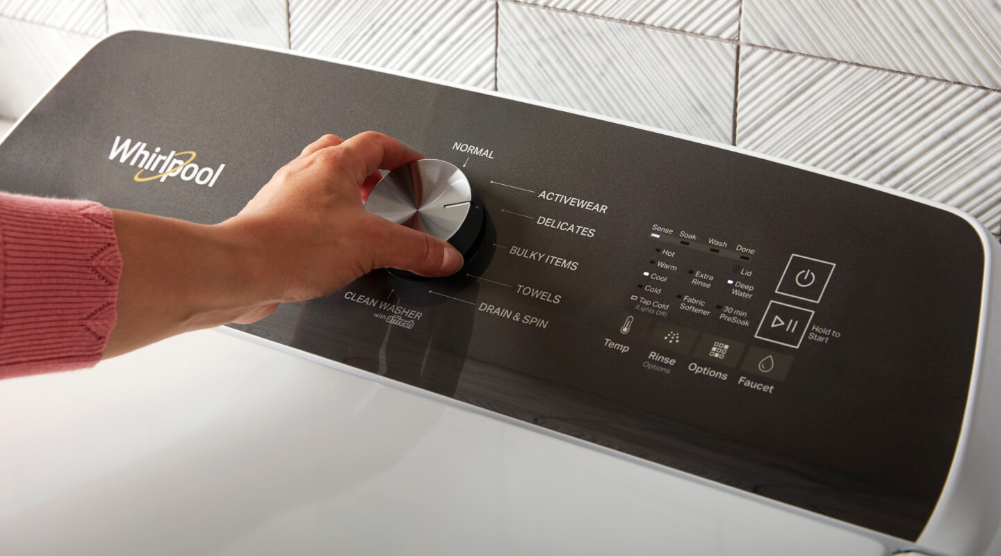 A person selecting the delicate cycle on a washer
