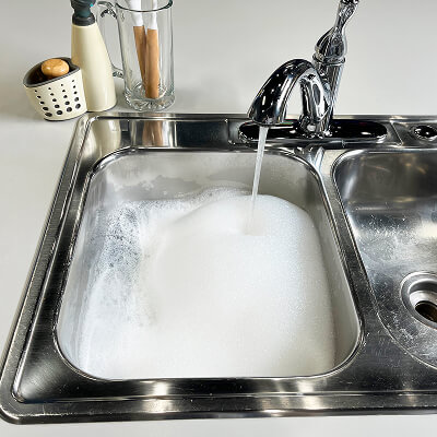 A sink filling with water and bubbles