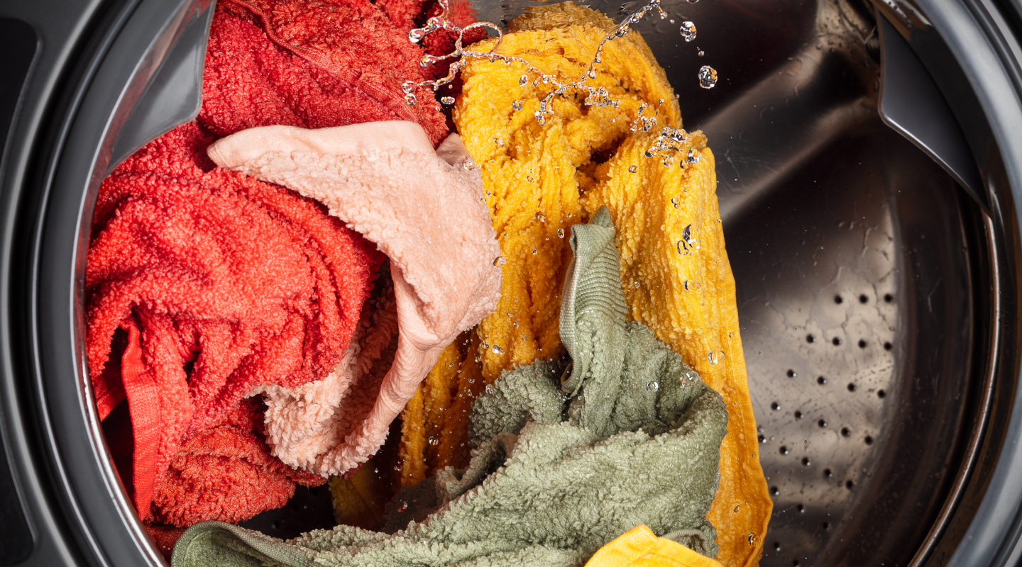 Towels of assorted colors being cleaned in a washing machine Towels of assorted colors being cleaned in a washing machine
