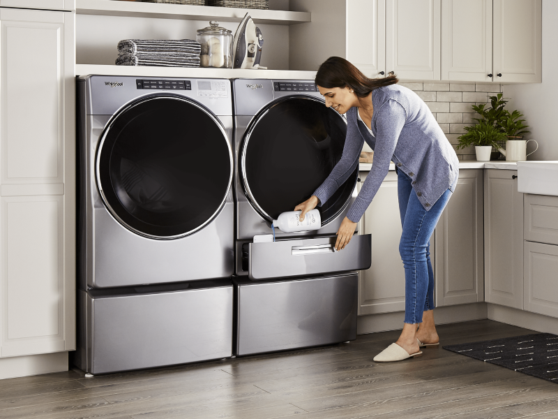 A woman pouring Swash® laundry detergent into a Whirlpool brand washing machine A woman pouring Swash® laundry detergent into a Whirlpool brand washing machine