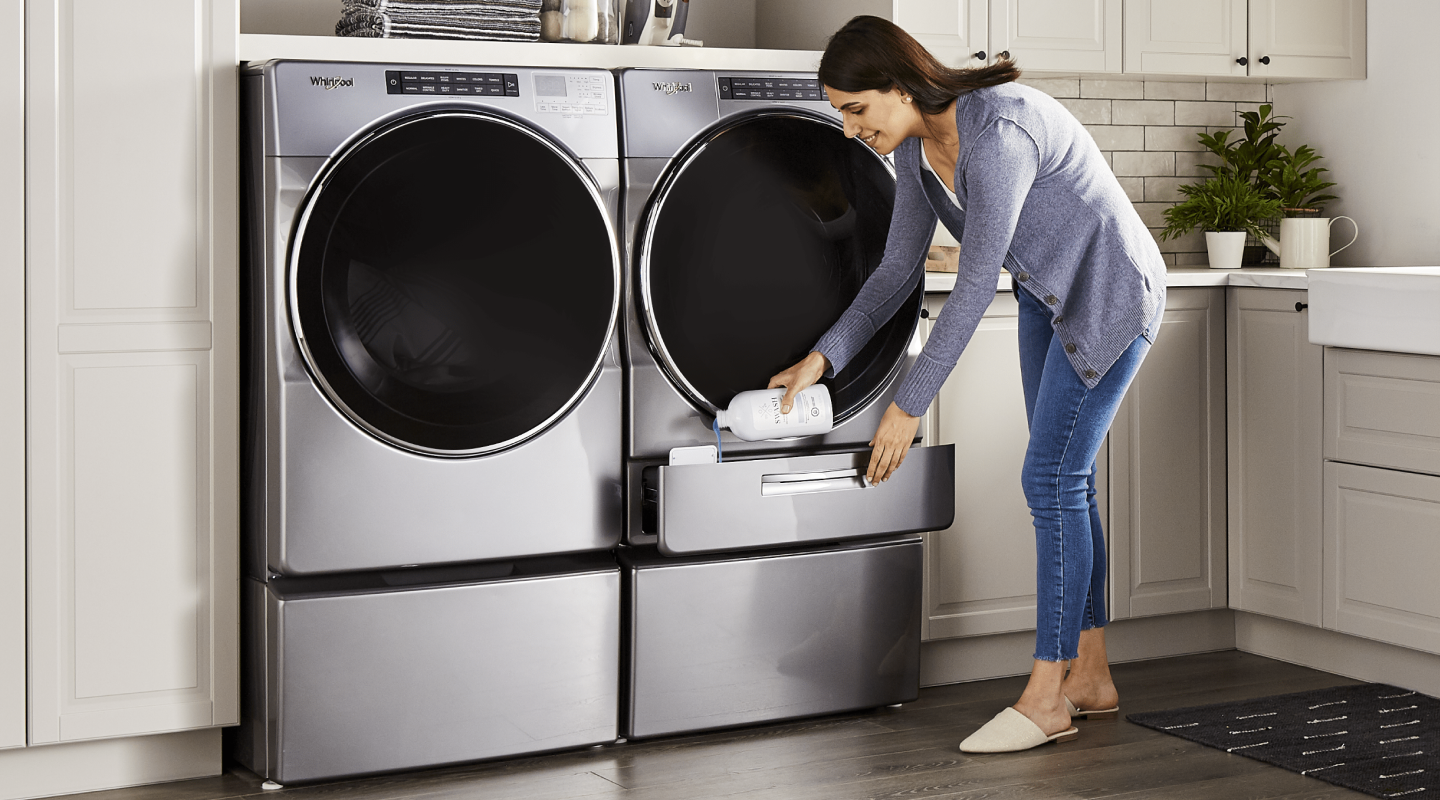 A woman pouring Swash® laundry detergent into a Whirlpool brand washing machine A woman pouring Swash® laundry detergent into a Whirlpool brand washing machine