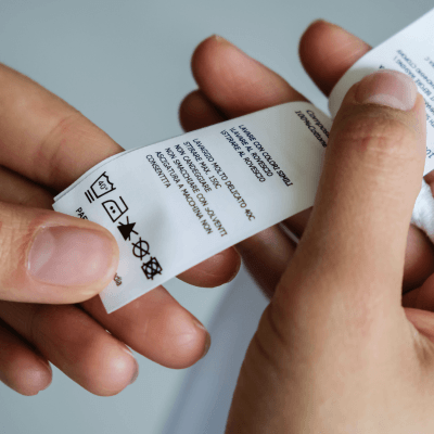 A person checking a care label on the inside of a piece of clothing
