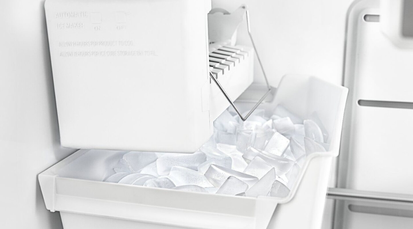 White ice maker inside freezer compartment with full ice bin