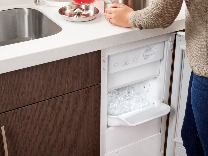 Person standing in front of an open undercounter ice maker