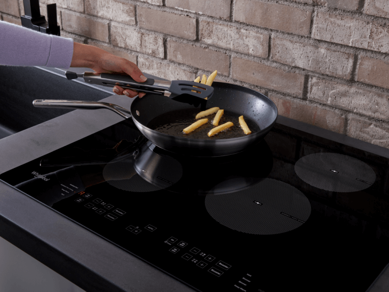 Person frying french fries in frying pan on stovetop Person frying french fries in frying pan on stovetop