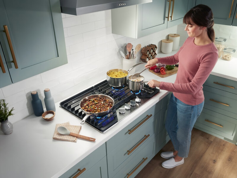 Person cooking a meal on a Whirlpool® Gas Cooktop Person cooking a meal on a Whirlpool® Gas Cooktop