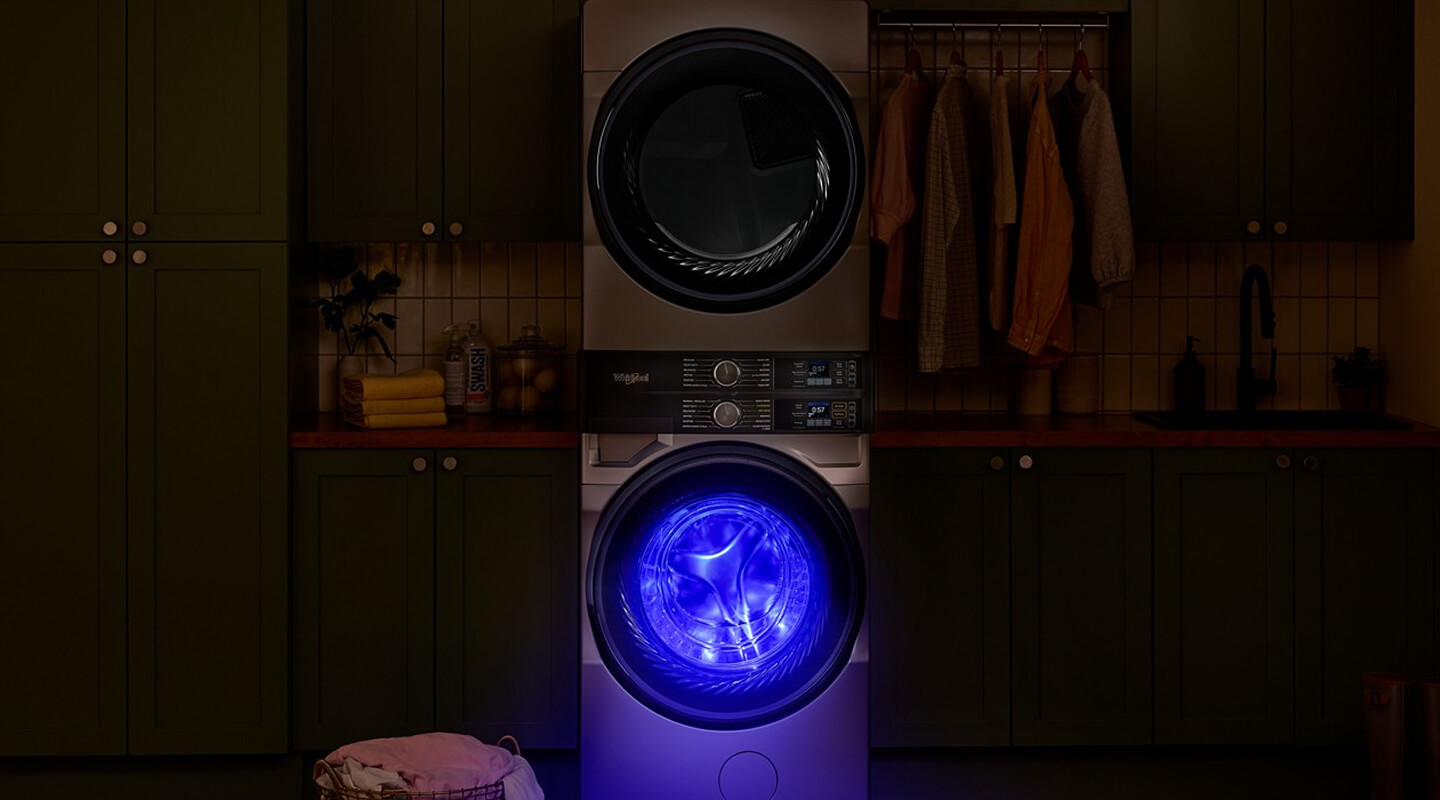 Blue light glowing from UV Clean Technology setting in a Whirlpool® Washer placed in a dark laundry room