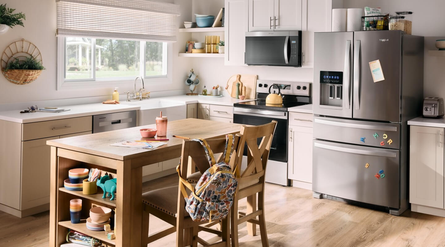 A French door bottom mount refrigerator in a kitchen with a wooden island and white countertops