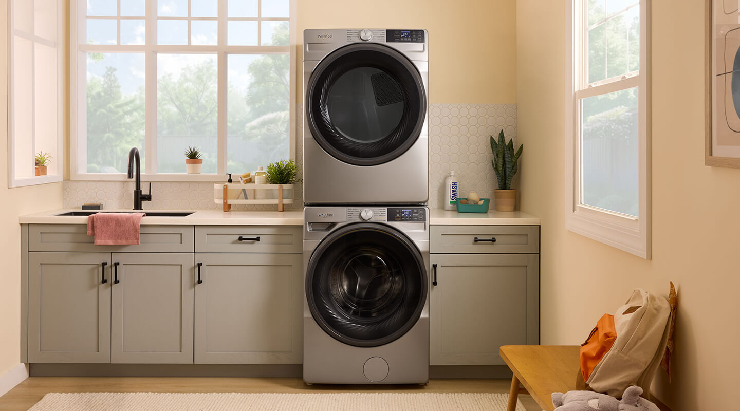 Stackable front load washer and dryer in a laundry room with gray cabinets