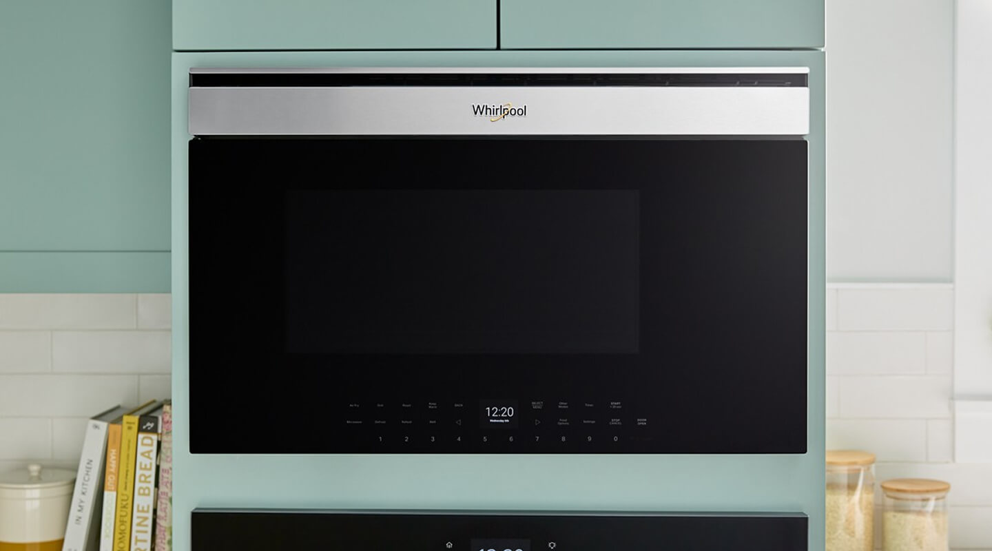 A built-in microwave set in light green cabinetry