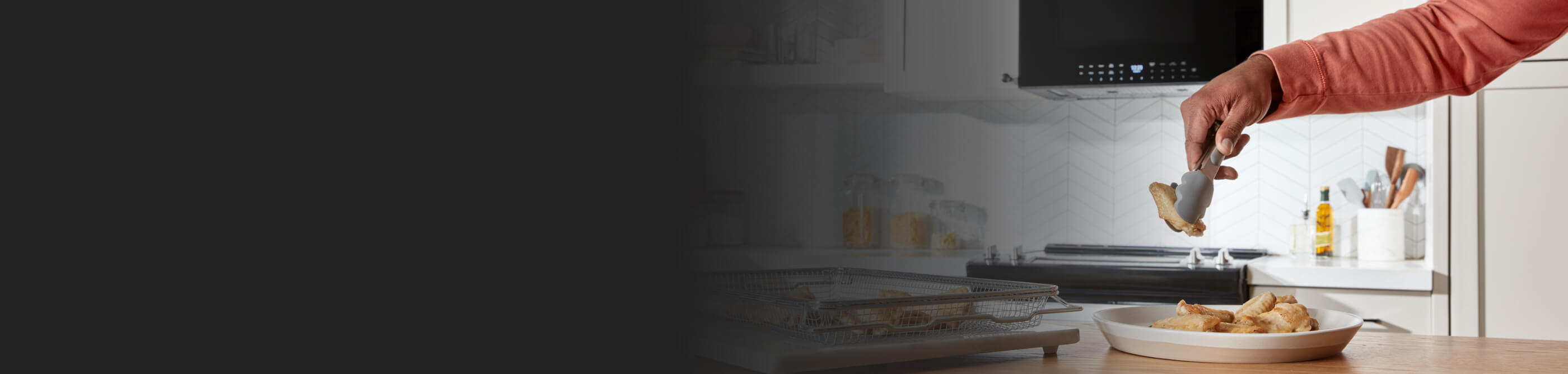 Person using tongs to remove chicken wings from air fry basket