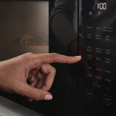 Person selecting settings on a microwave touchpad