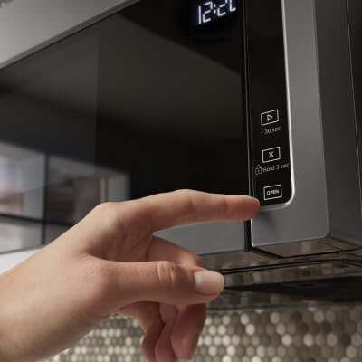 Person pressing touch controls on over-the-range microwave