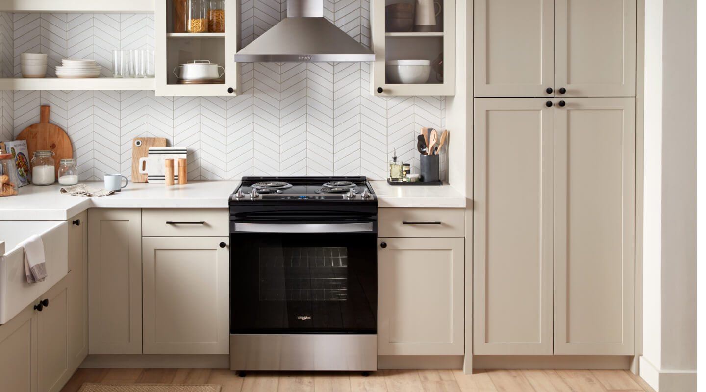 A range and range hood surrounded by white cabinetry