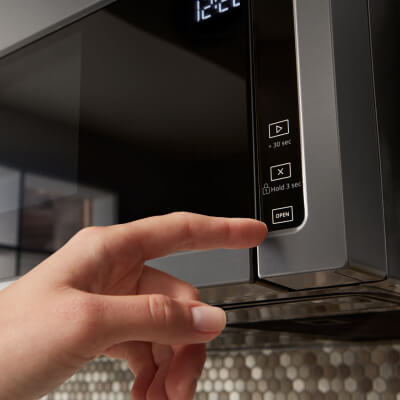 Person selecting a cook option on a Whirlpool® over-the-range microwave