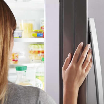 Close-up of a person’s hand on a fingerprint-resistant refrigerator door