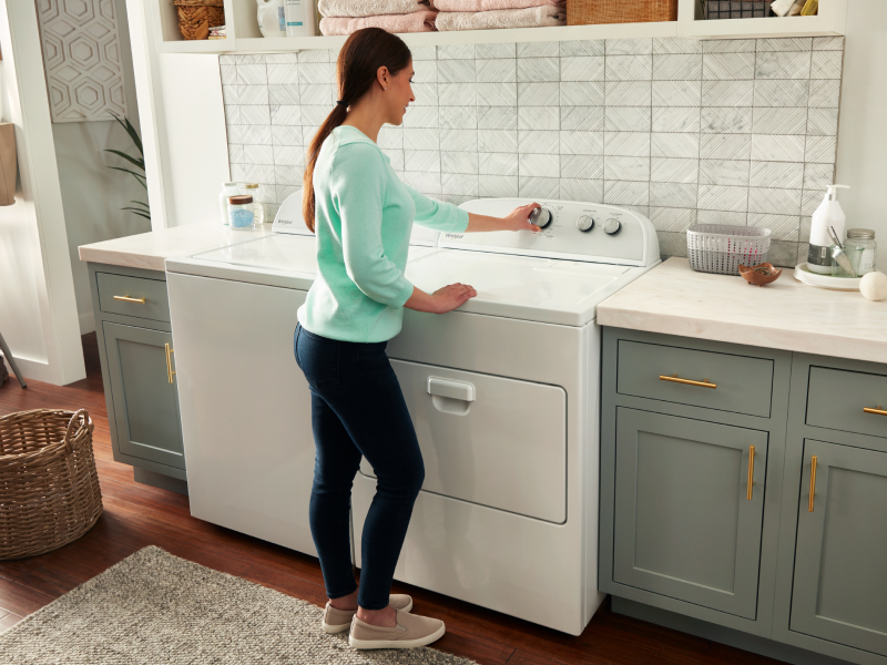 Woman selecting a cycle on a white Whirlpool® dryer Woman selecting a cycle on a white Whirlpool® dryer