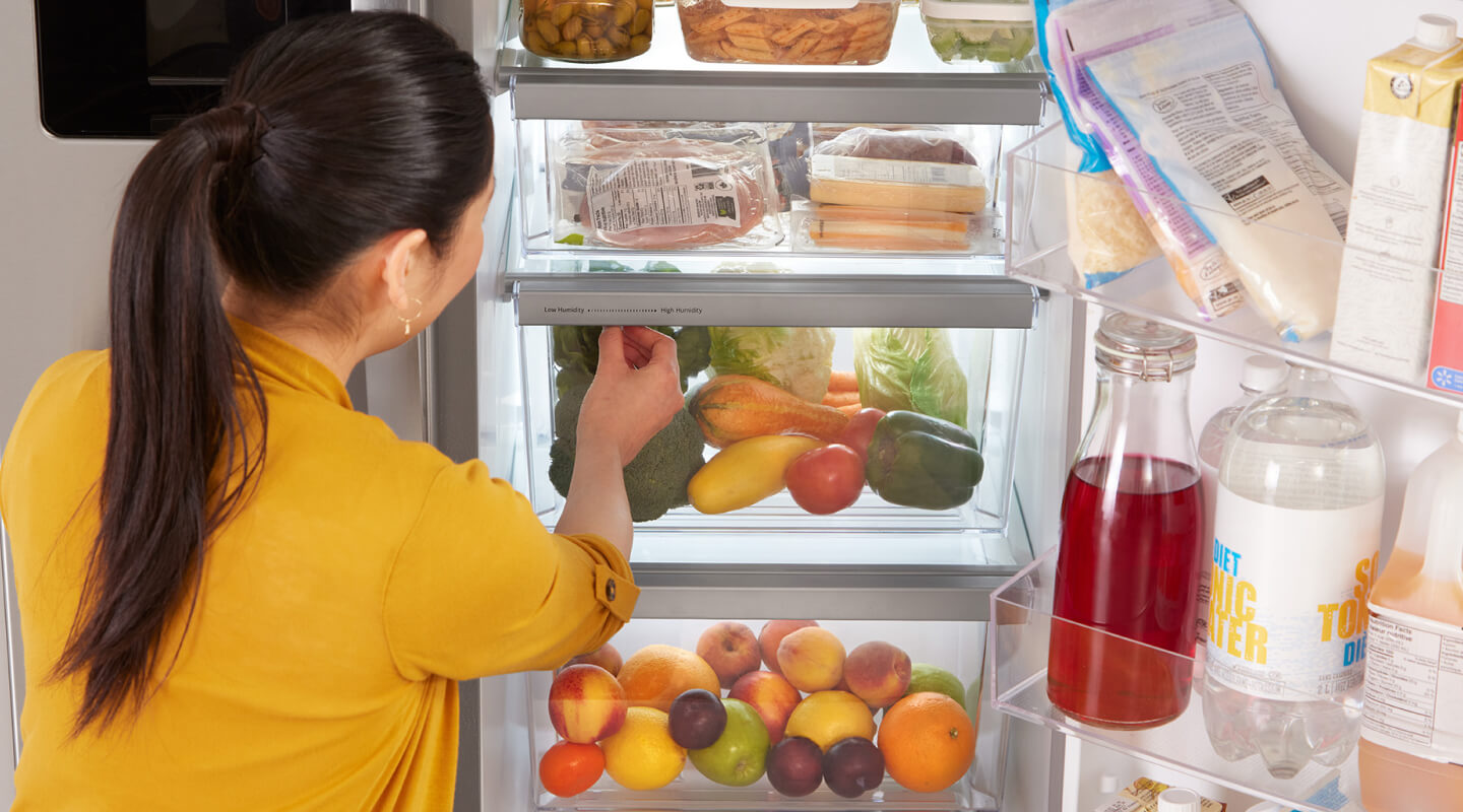 A person getting food out of their fridge A person getting food out of their fridge