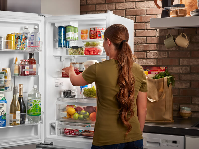 A person standing in front of their open fridge