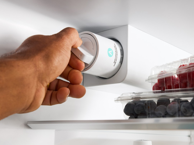 A person changing a fridge filter