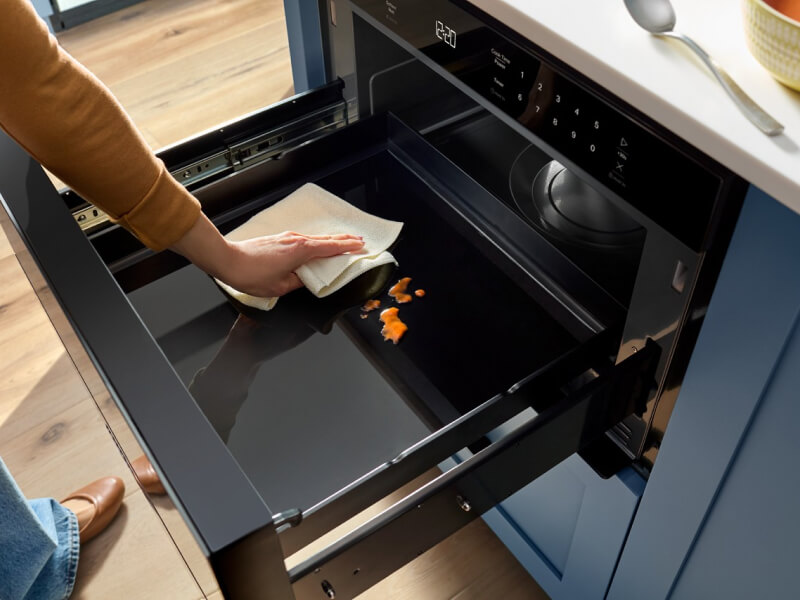 A person cleaning a Whirlpool® Microwave Drawer