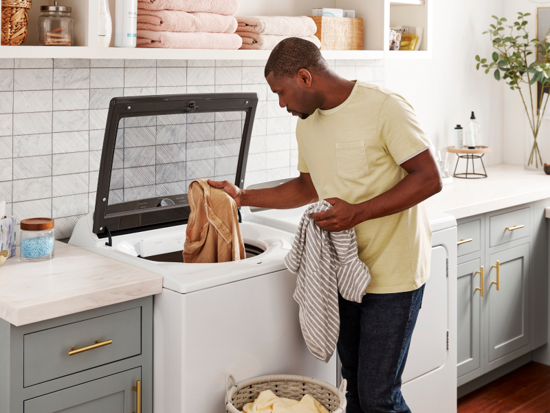 Person removing towels from a Whirlpool® top load washer Person removing towels from a Whirlpool® top load washer