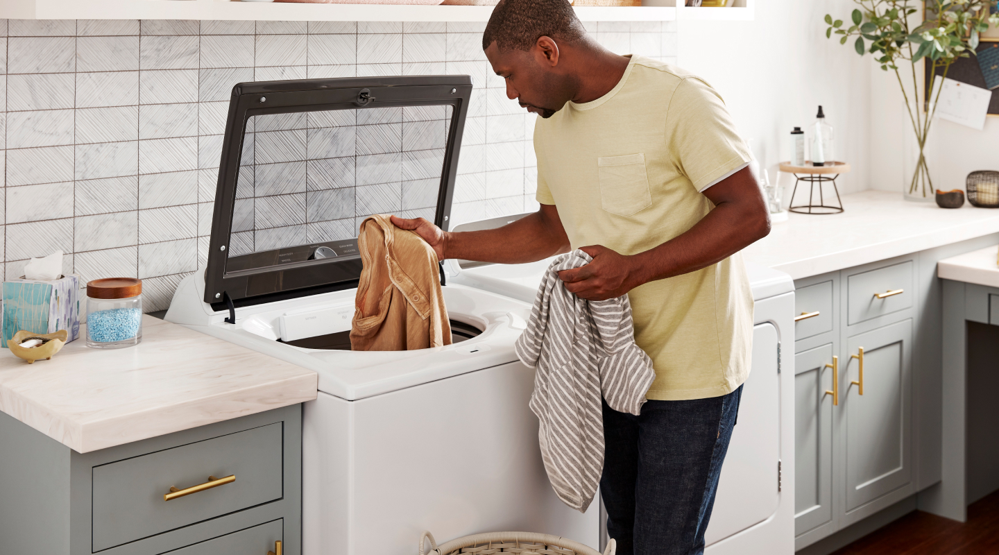 Person removing towels from a Whirlpool® top load washer Person removing towels from a Whirlpool® top load washer