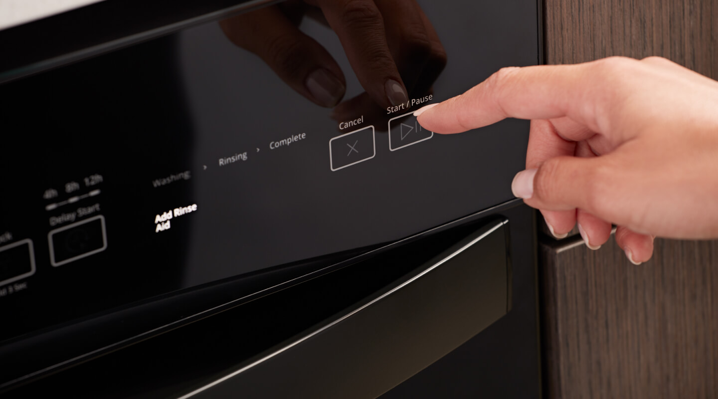 A hand selecting a control on a Whirlpool® Front Control Dishwasher