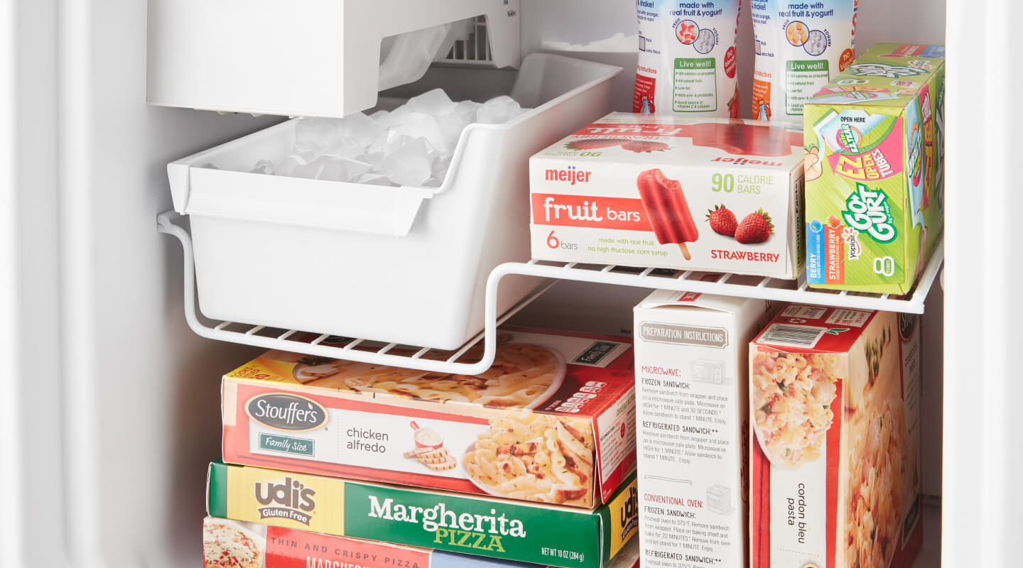 An open freezer packed with frozen food, including popsicles