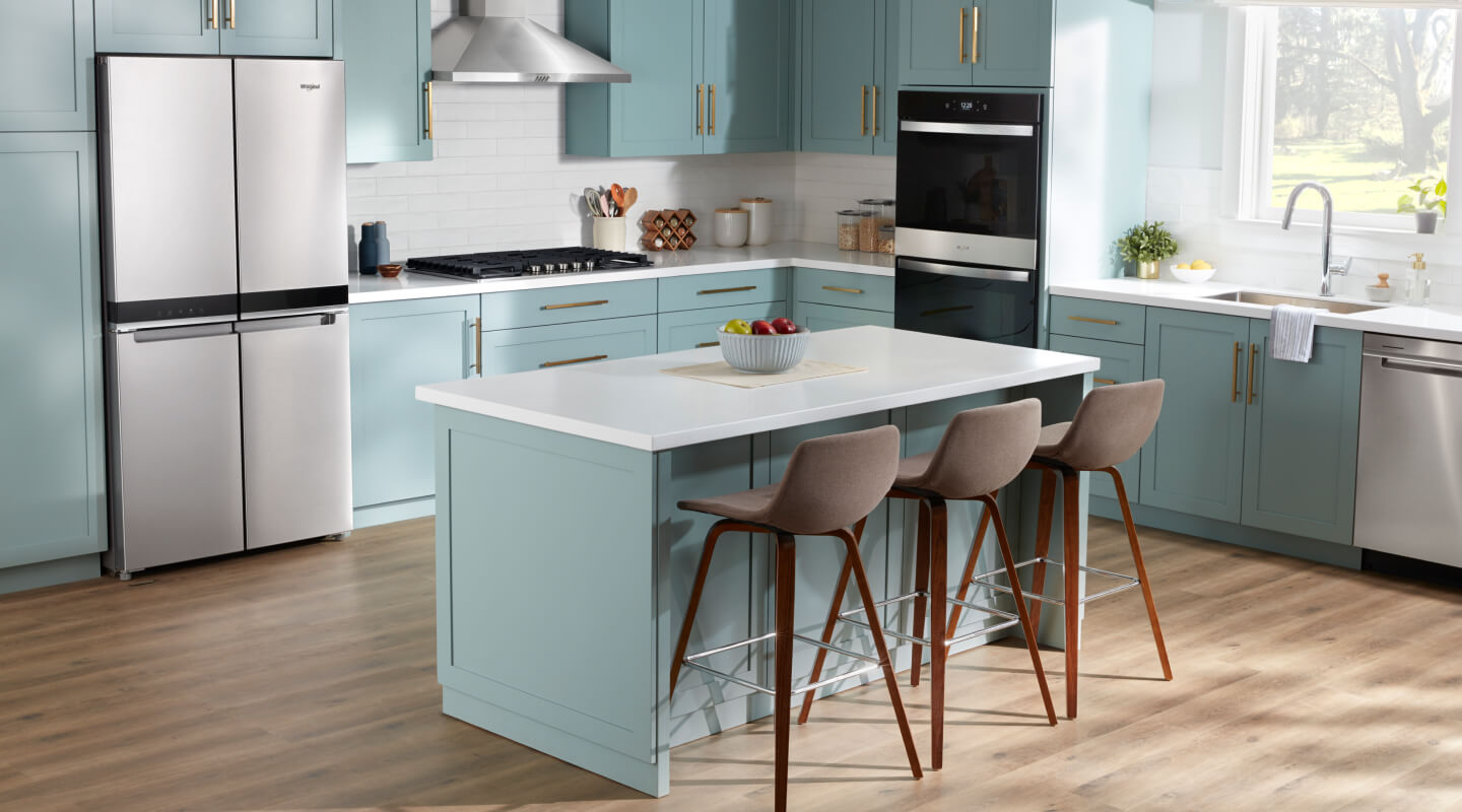 The interior of a kitchen with blue cabinetry and a 4 door refrigerator from Whirlpool brand