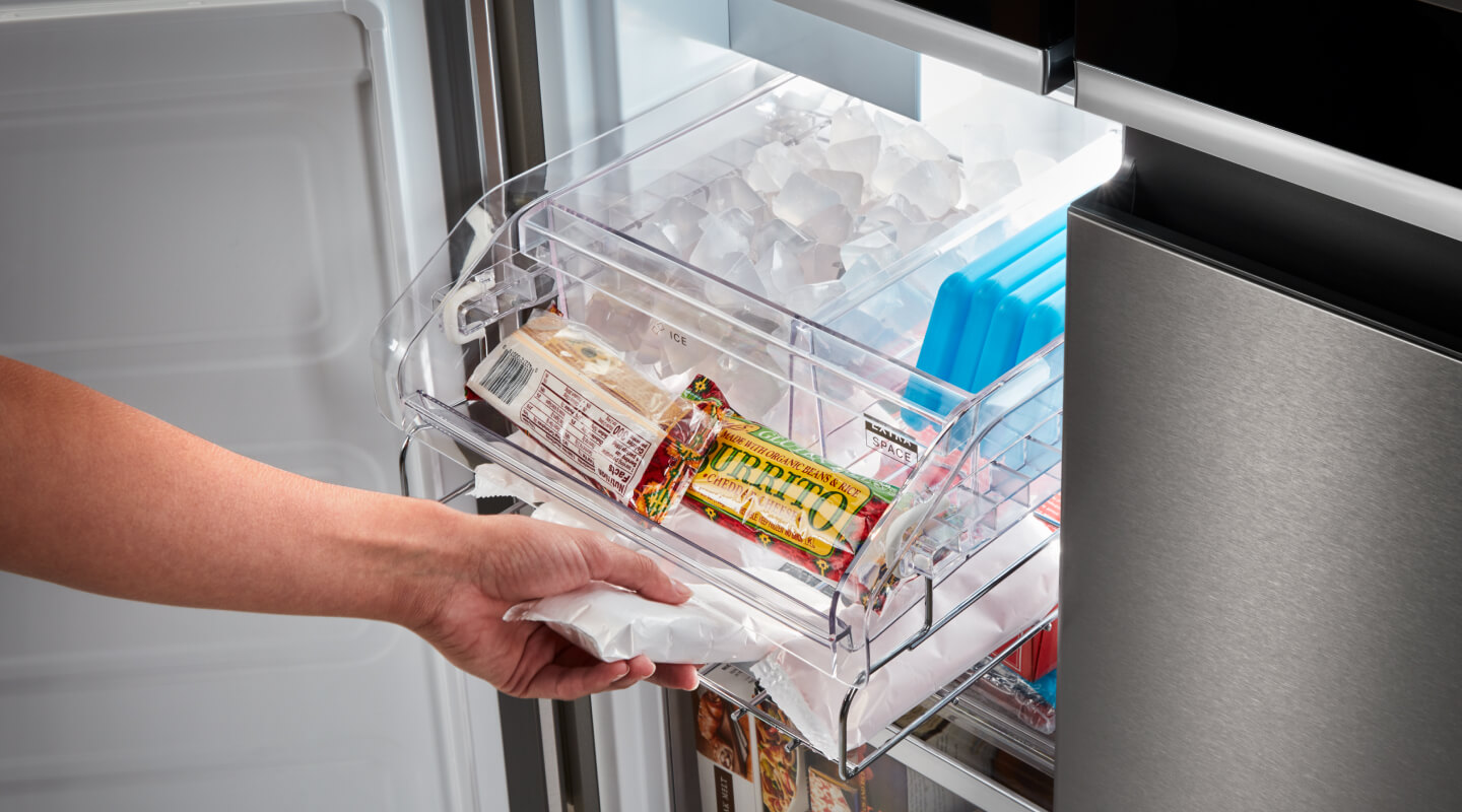 A person taking a popsicle out of a bottom freezer refrigerator