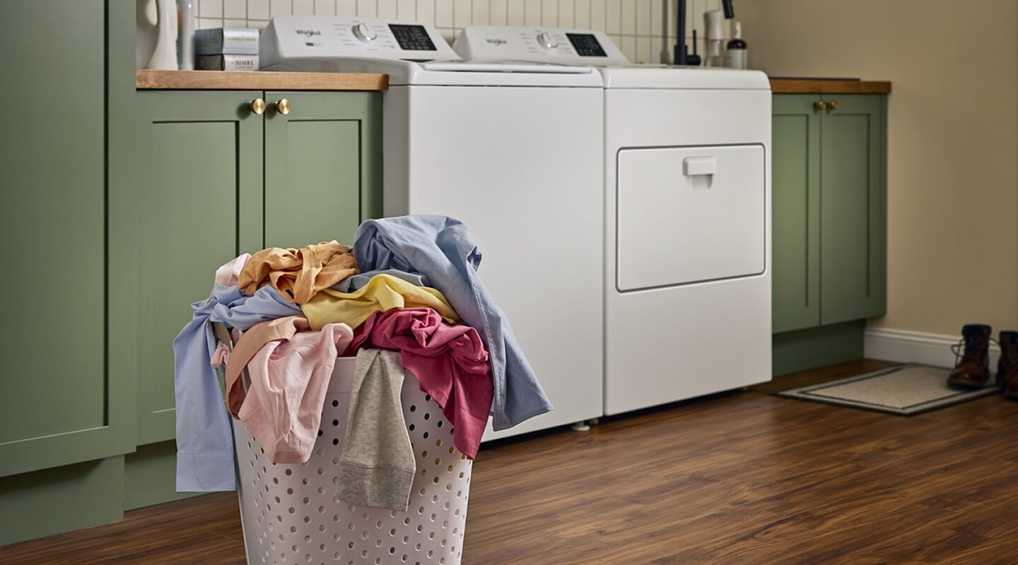 A basket of laundry in front of a washer and dryer set in a laundry room