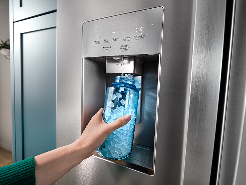 A person dispensing nugget ice cubes into a translucent blue bottle