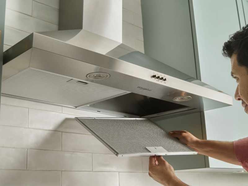 A person changing the filter on a range hood. A person changing the filter on a range hood.