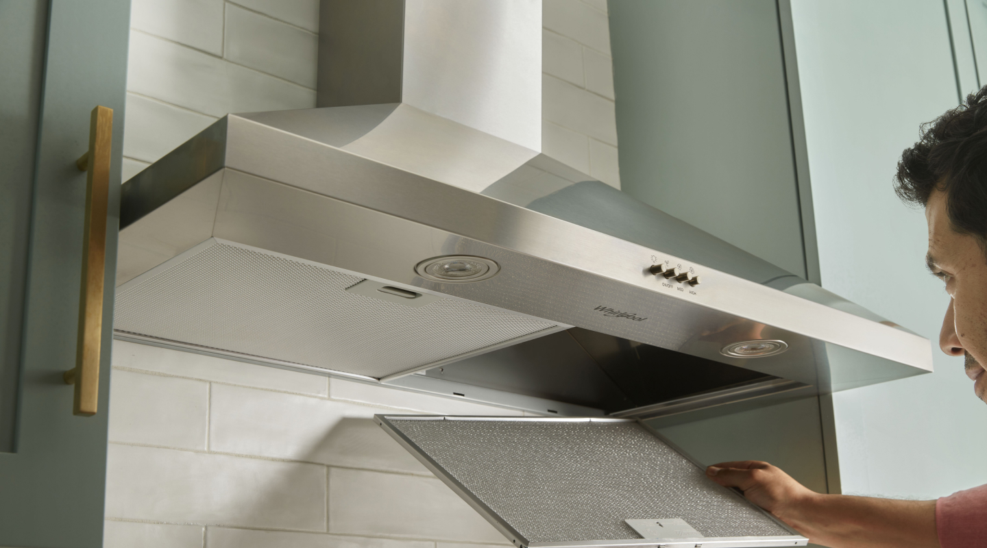 A person changing the filter on a range hood. A person changing the filter on a range hood.